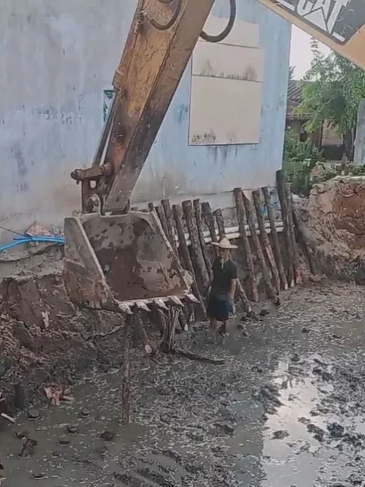 Excavator with hydraulic breaker lifting wooden posts without clamp, illustrating safety risk